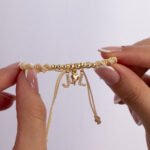Pulsera De Oro 18K Con Esferas Esferas  Hilo Color Beige Dijes Letra J Y L Y Dije Tres Gracias - Imagen 2